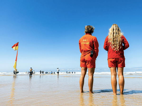 RNLI lifeguards Vittoria Farmer (from Autralia) and Theresa Morokutti (from Austria) monitoring the sea at Mawgan Porth beach, Newquay. Picture: RNLI/Nathan Williams