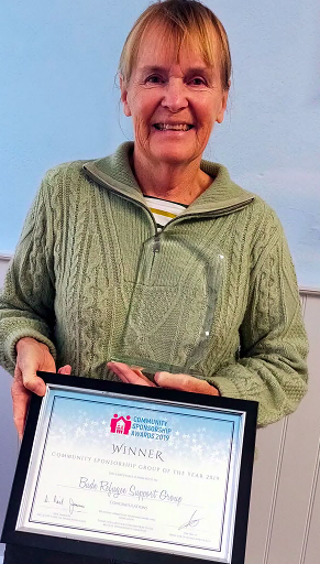Mrs Mary Whibley, of the Bude Refugee Support Group, with a trophy and certificate marking its crowning as Community Sponsorship Group of the Year 2019