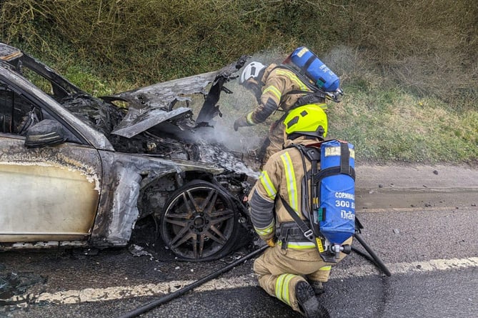 The wreckage of the car being extinguished by officers
