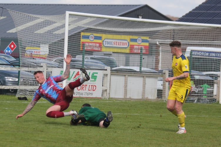 Launceston midfielder goes over in the box as Wendron goalkeeper Zach Telling collects.