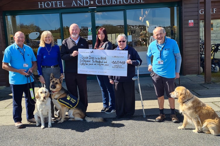 Bryan pictured in the centre holding the cheque with volunteers from Guide Dogs