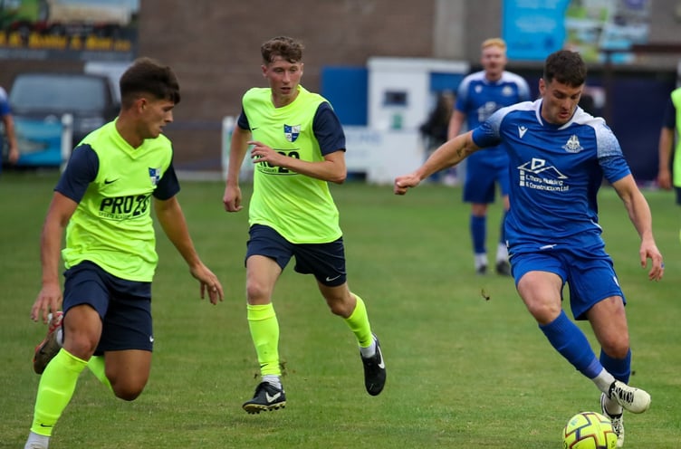 Camelford centre-half Dan Hocking keeps his eye on the ball as former Camels midfielder Matt Andrew advances forward. (Picture: Colin Hilton).