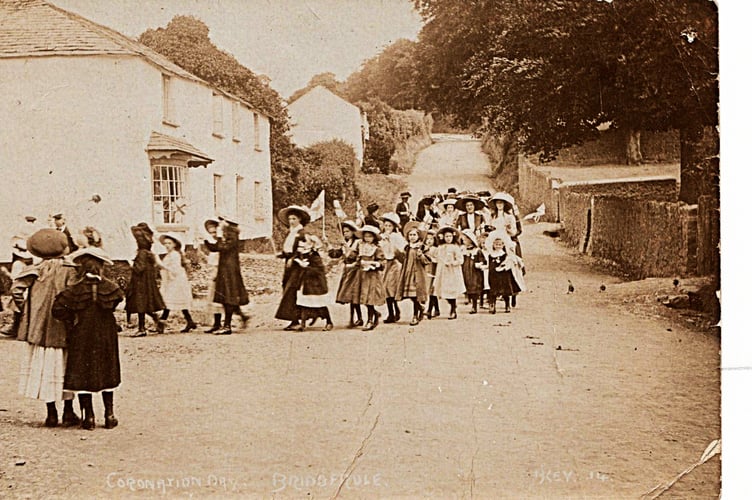 The Post is grateful to Rose Hitchings of Bridgerule for supplying this image of a procession of ladies and children with "lovely hats". Rose says of this image: "The house behind them used to be Bridgerule Post Office and the wall to the right belongs to the school - now the Bridgerule Primary School and very much changed today from this photo. The old post card is entitled 'Coronation Day' and there's a bit of flag waving to be seen."